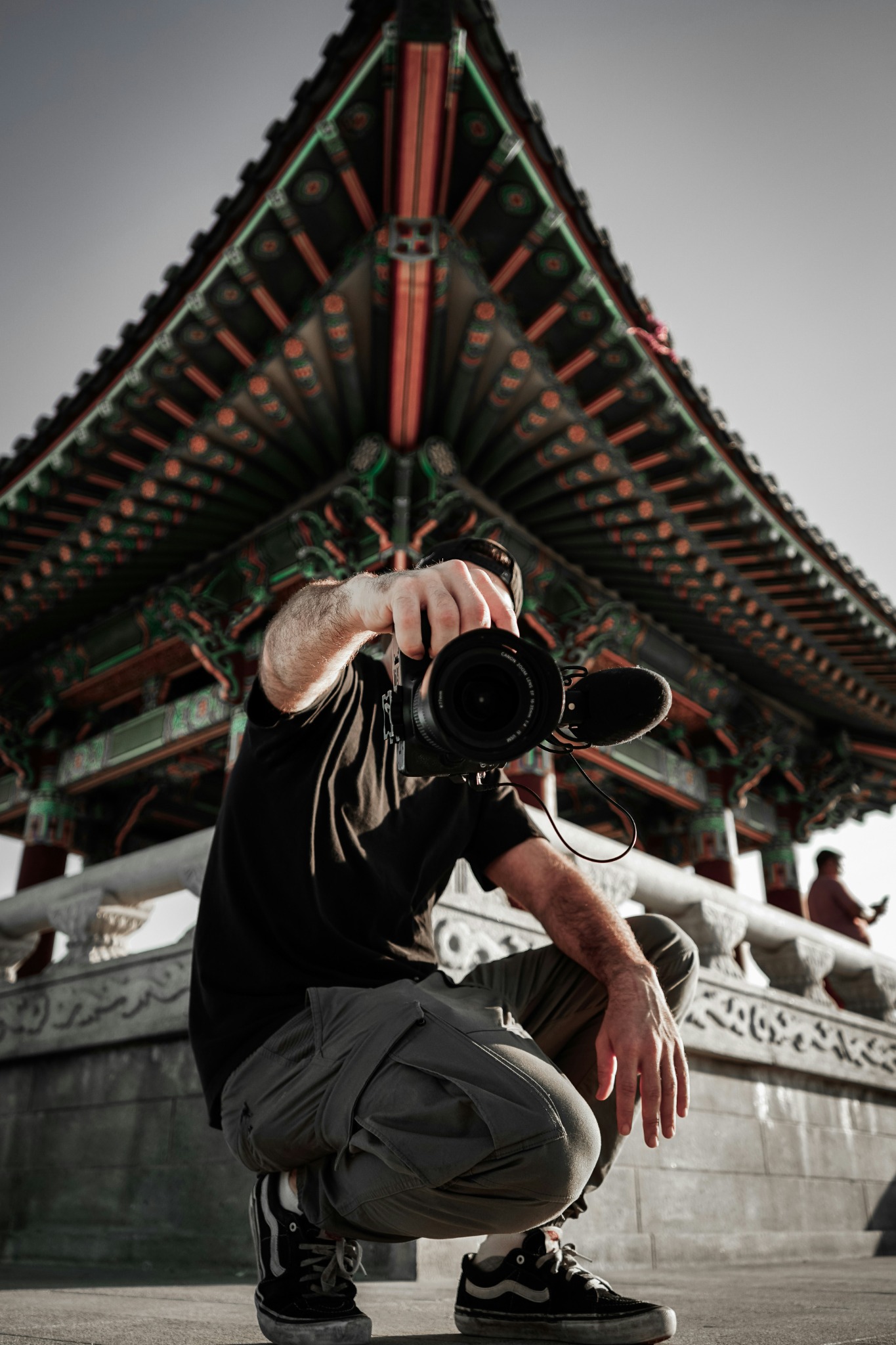 A photographer crouching with a camera in front of ornate architecture