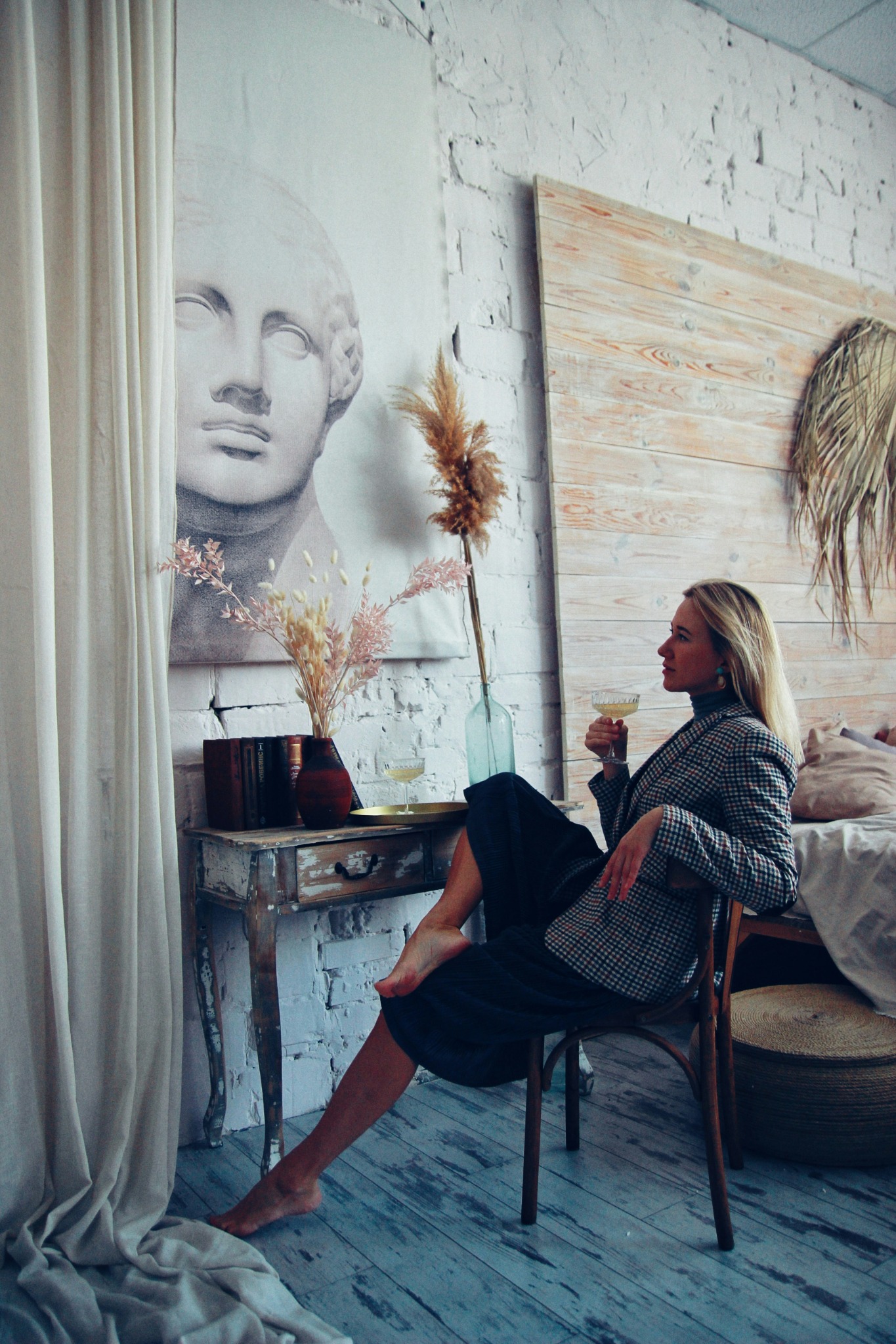 A woman seated in a softly styled interior holding a coupe glass
